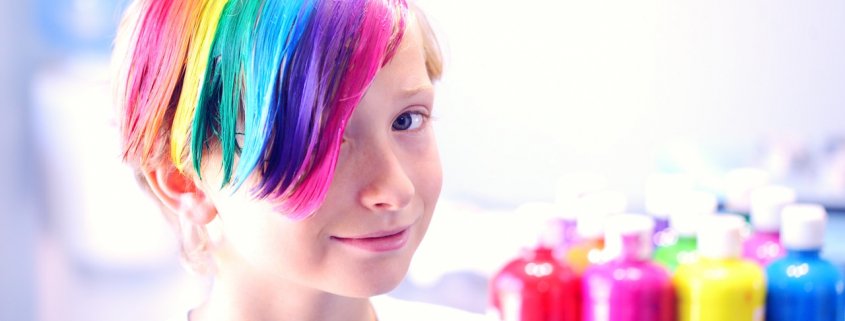 child with multicolored dyed hair with hair dye sitting in background